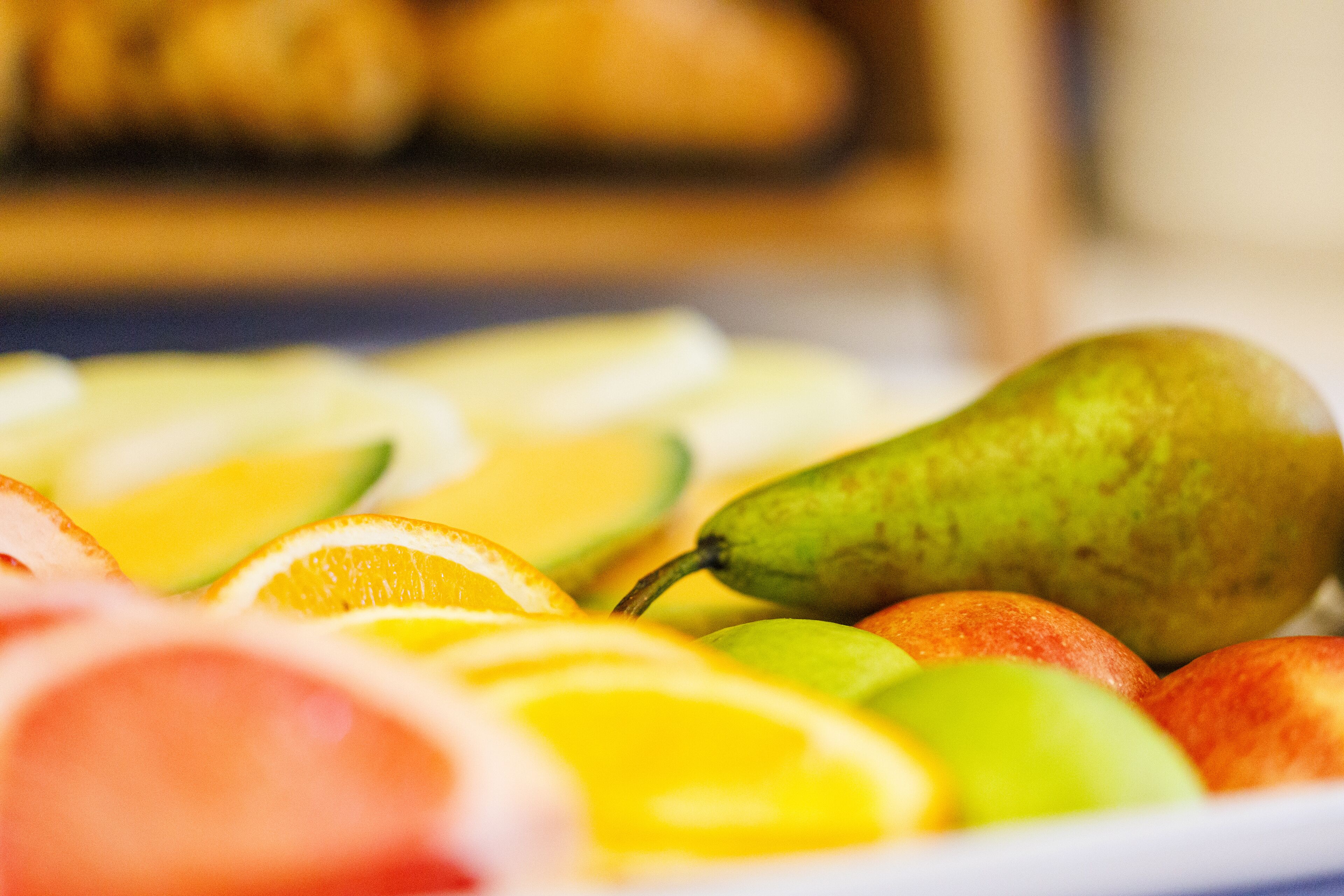 A close-up of a fruit platter with slices of oranges, apples, and a pear.