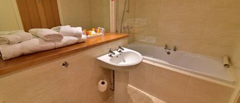 A bathroom with a sink, toilet, and bathtub. There are towels on the counter and toiletries.
