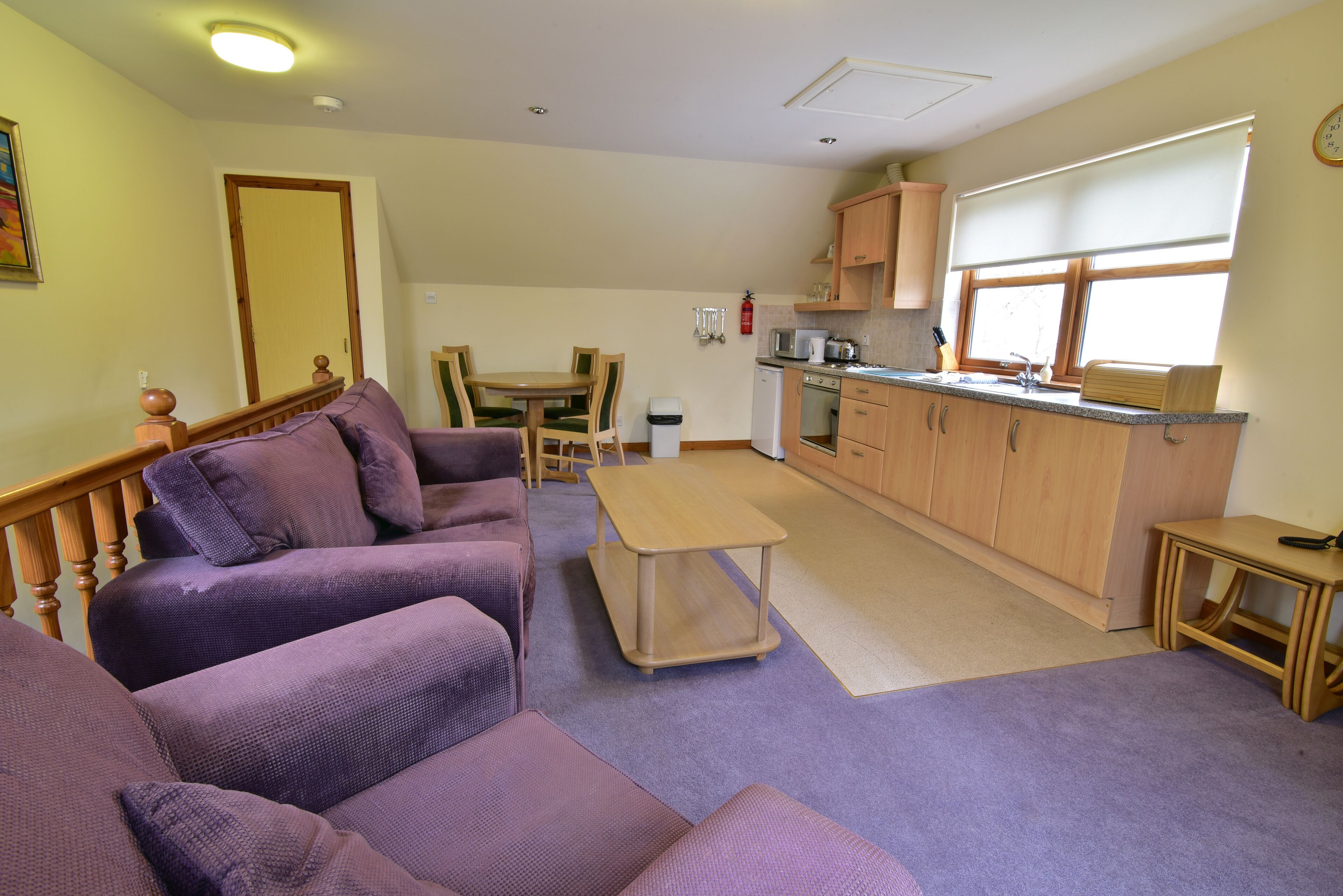 A compact living space with a sofa set, a dining table, and a kitchenette.