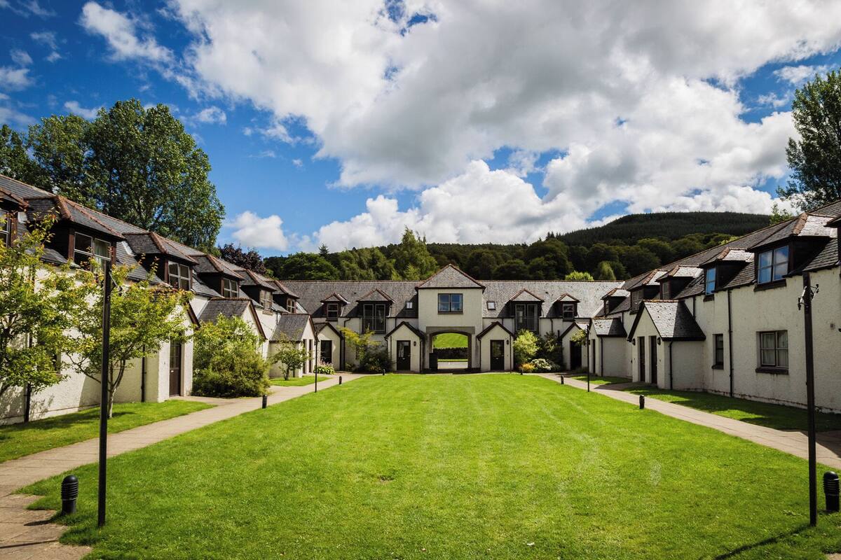 A courtyard with a central lawn, surrounded by buildings with pitched roofs and multiple windows.