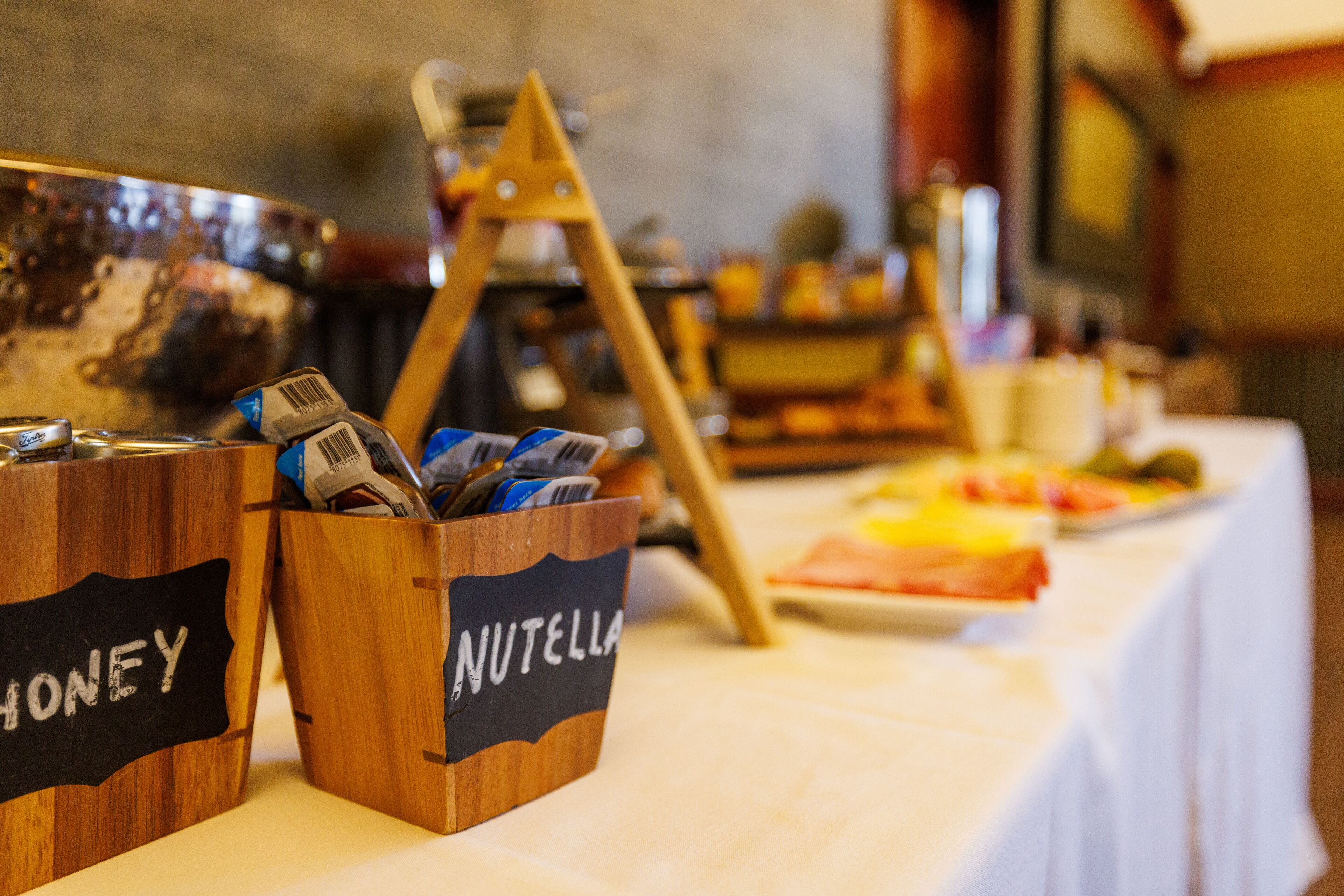 A buffet table with labeled containers for honey and Nutella.
