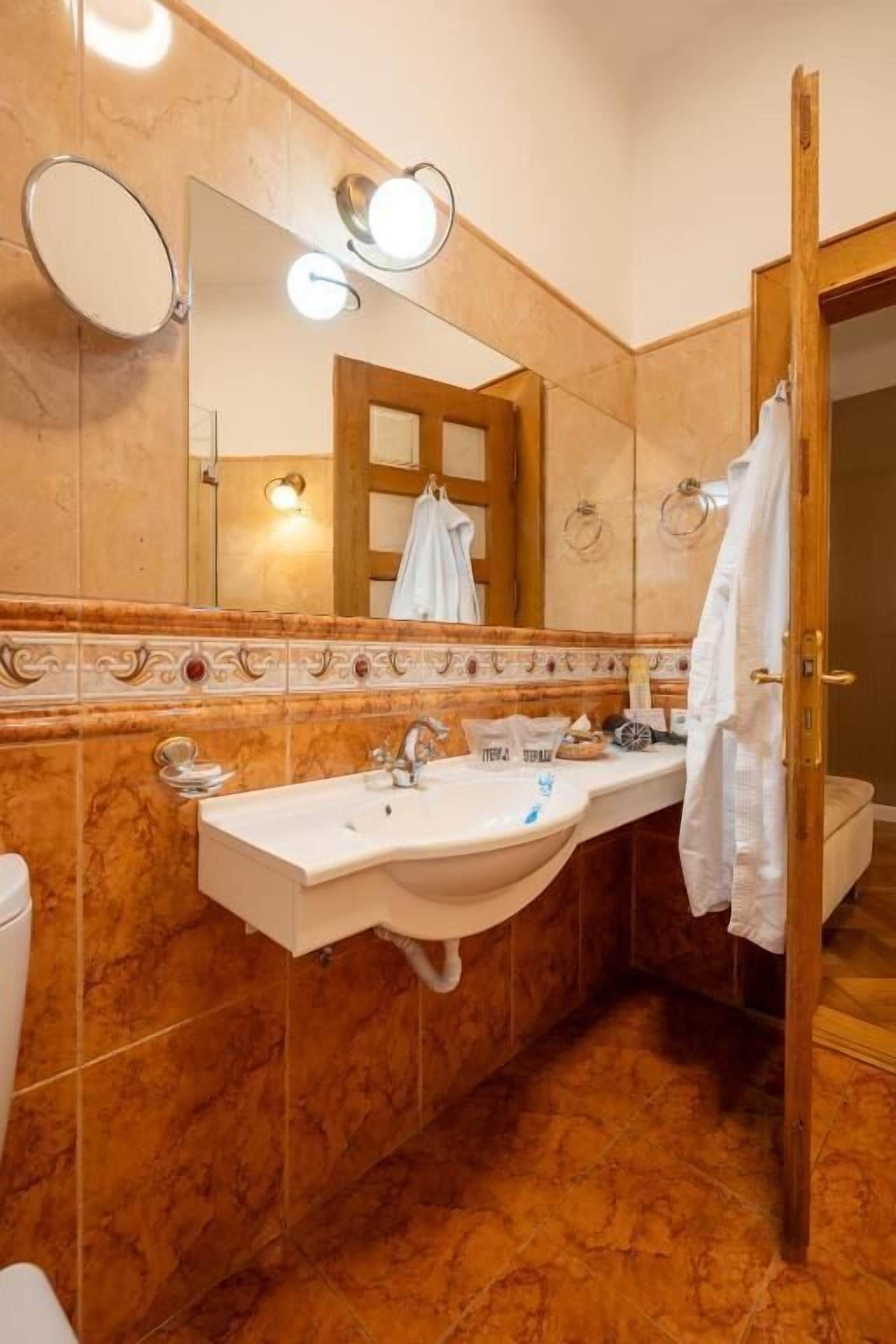 Un baño con pared de mármol, lavabo con espejo y un perchero para toallas.