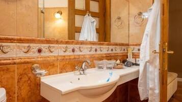 Un baño con pared de mármol, lavabo con espejo y un perchero para toallas.