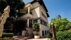 Ein mehrgeschossiges Gebäude mit Balkon, Steinstufen und Pflanzkübeln.