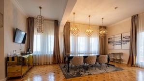 A dining area with a wooden herringbone floor, a black dining table with six chairs, and three hanging crystal chandeliers.