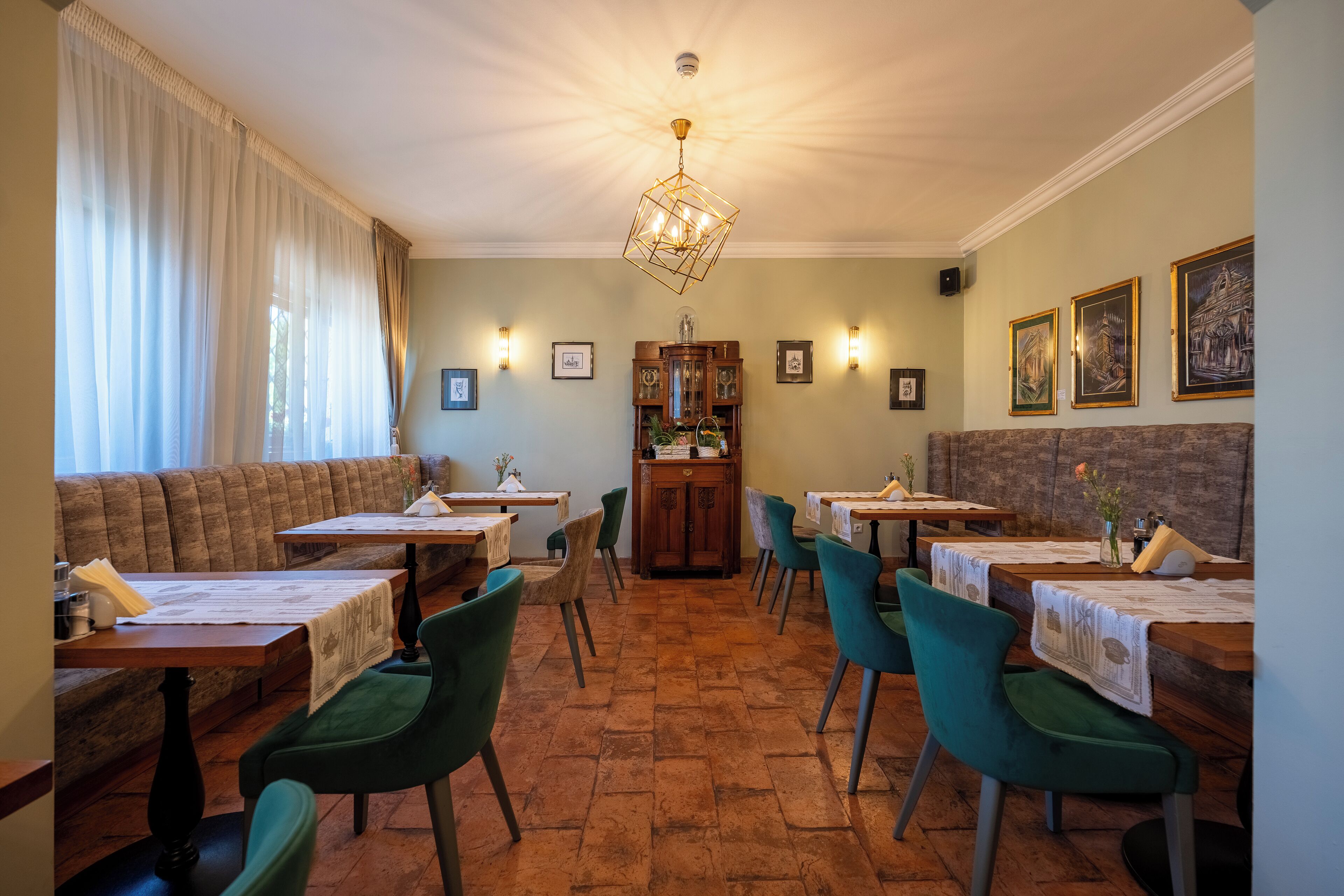 A dining area with wooden tables and chairs, a chandelier, and framed pictures on the walls.