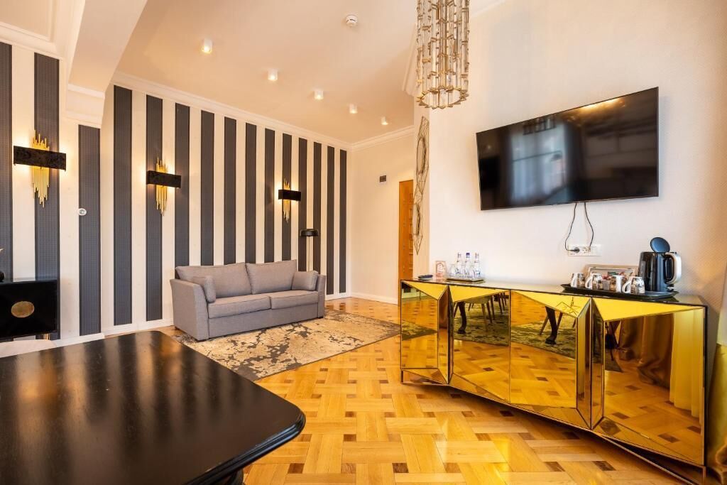 A modern living room with a sofa, a coffee table, a TV mounted on the wall, and a decorative mirror cabinet.