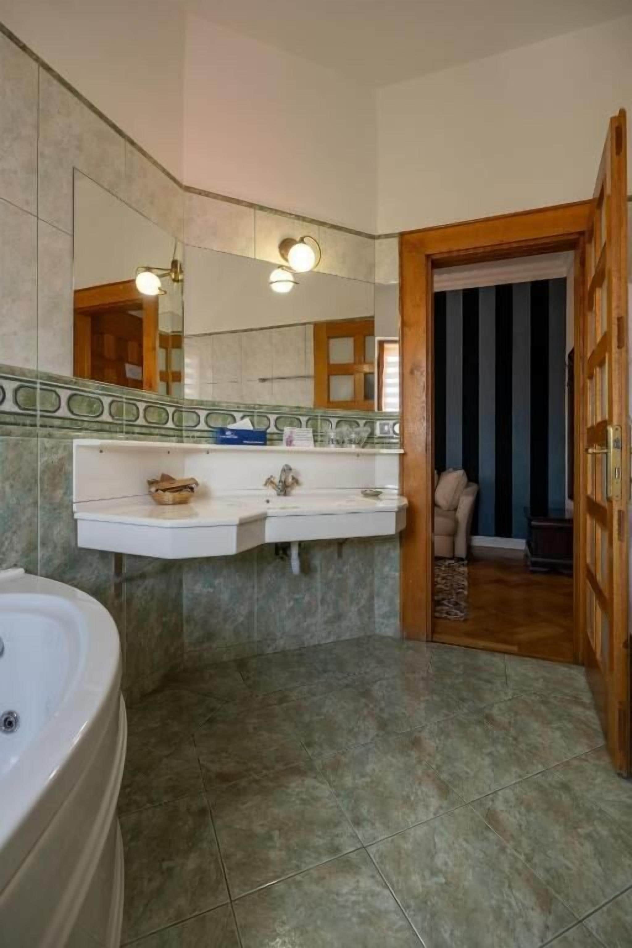 A bathroom with a double sink, a large mirror, and a bathtub.