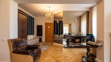 Ein geräumiges Wohnzimmer mit Ledersessel, Couchtisch aus Holz und einer Kristallleuchtre.