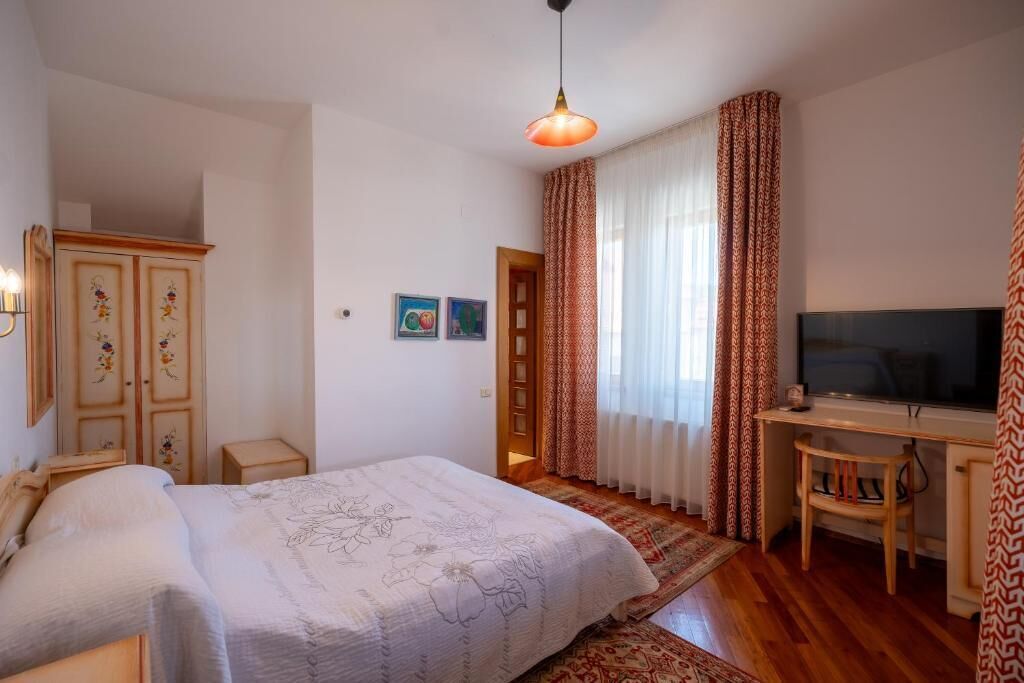 Une chambre à coucher avec un lit, un bureau, une télévision et une armoire.