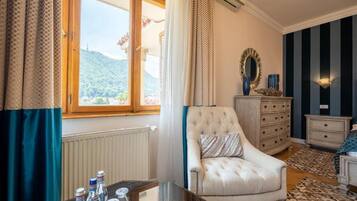 A room with a large window, a tufted armchair, a dresser, and a mirror.