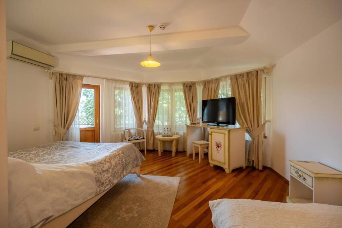 Ein Schlafzimmer mit zwei Betten, einem Schreibtisch, einem Stuhl, einem Fernseher und einem Fenster mit Vorhängen.