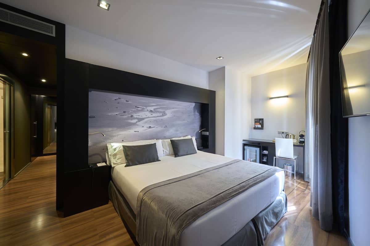 Moderni hotellihuone, jossa on suuri sänky, sisäänrakennettu työpöytä ja näkymä kaupunkiin.