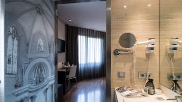 Un baño moderno con pared de mármol, espejo redondo y secador de pelo.