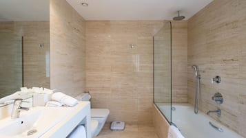 Un baño moderno con ducha de vidrio, lavamanos blanco y retrete.