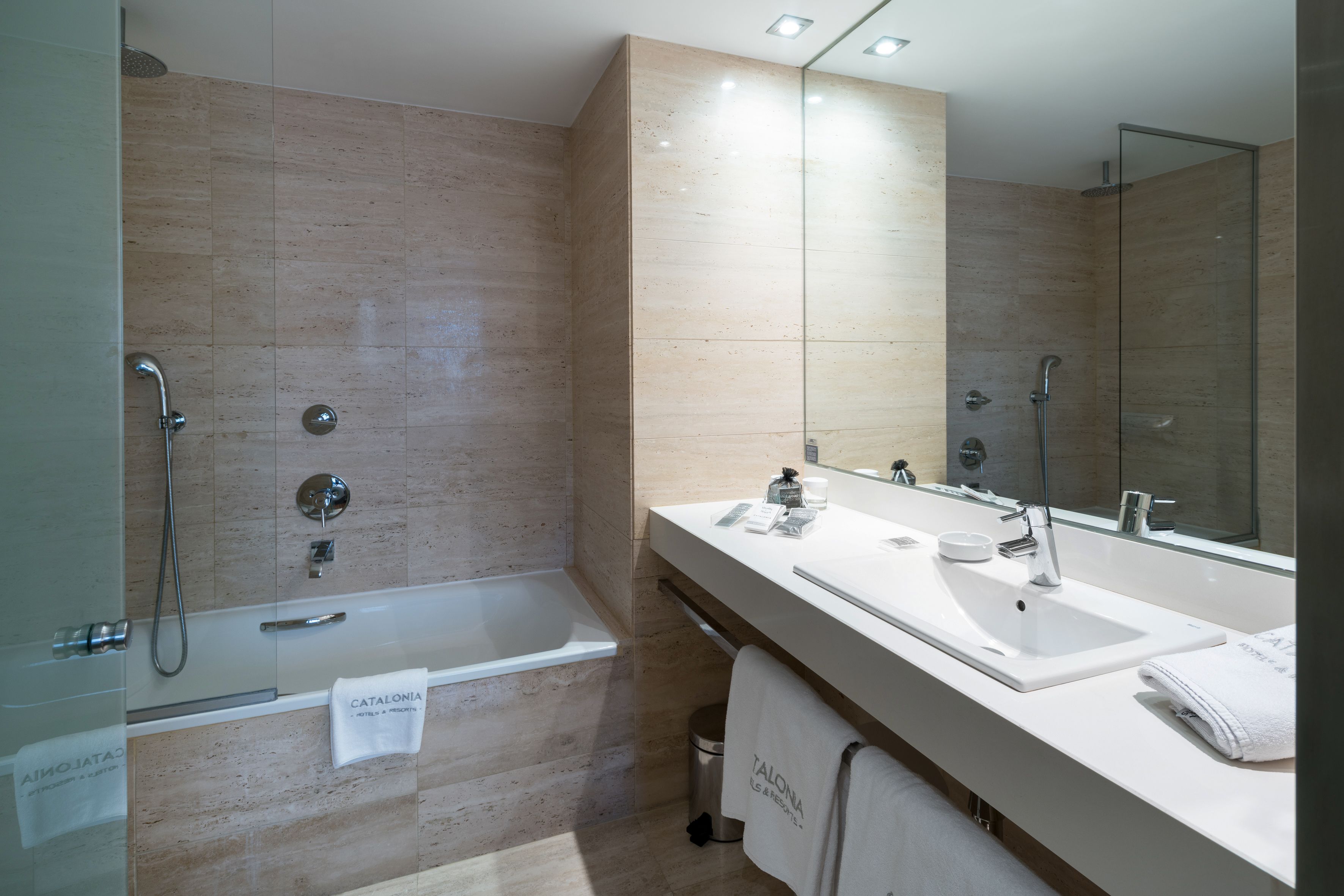 A modern bathroom with a bathtub, two sinks, and a large mirror.