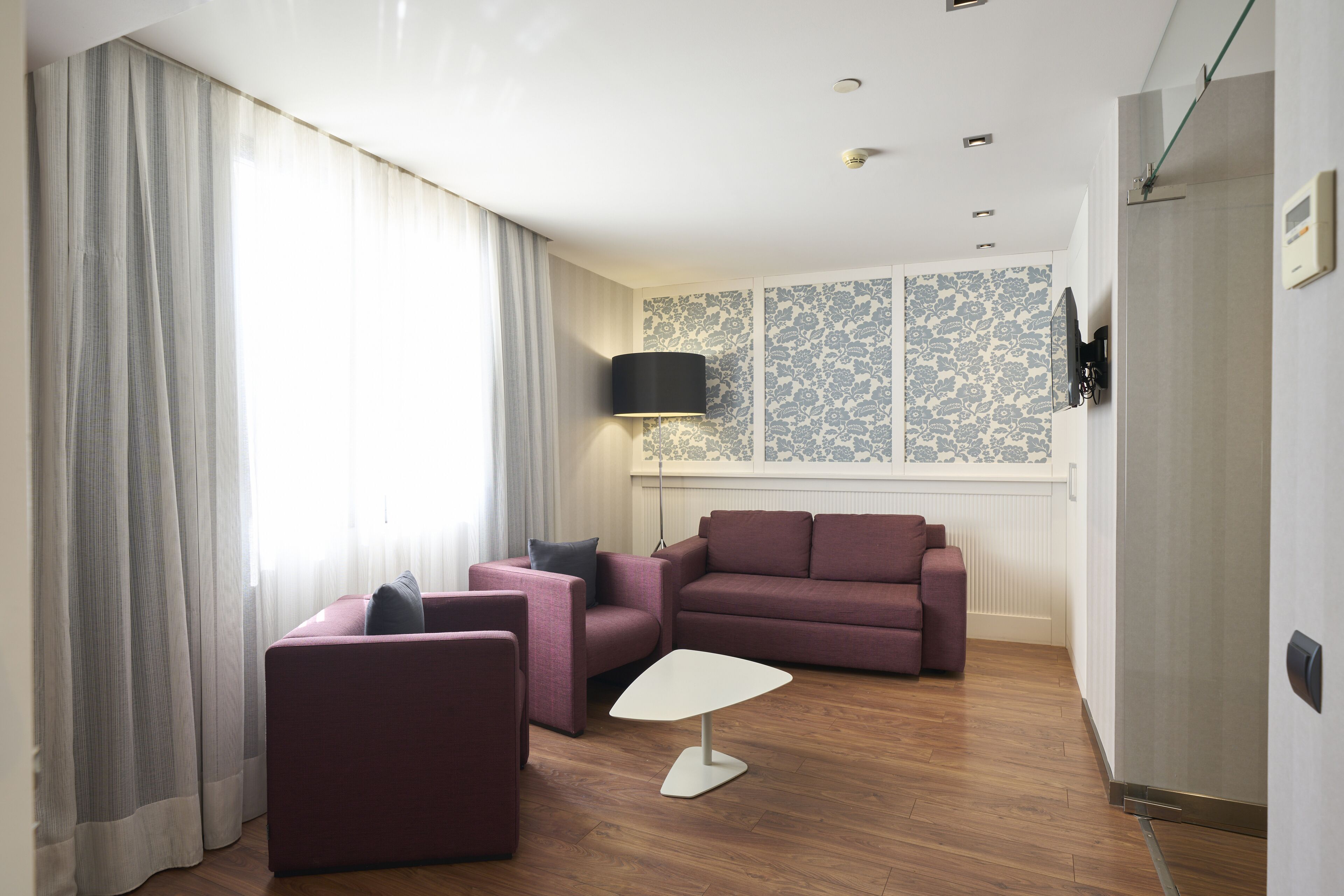A modern living room with a sectional sofa, a small white table, and a wall-mounted TV.