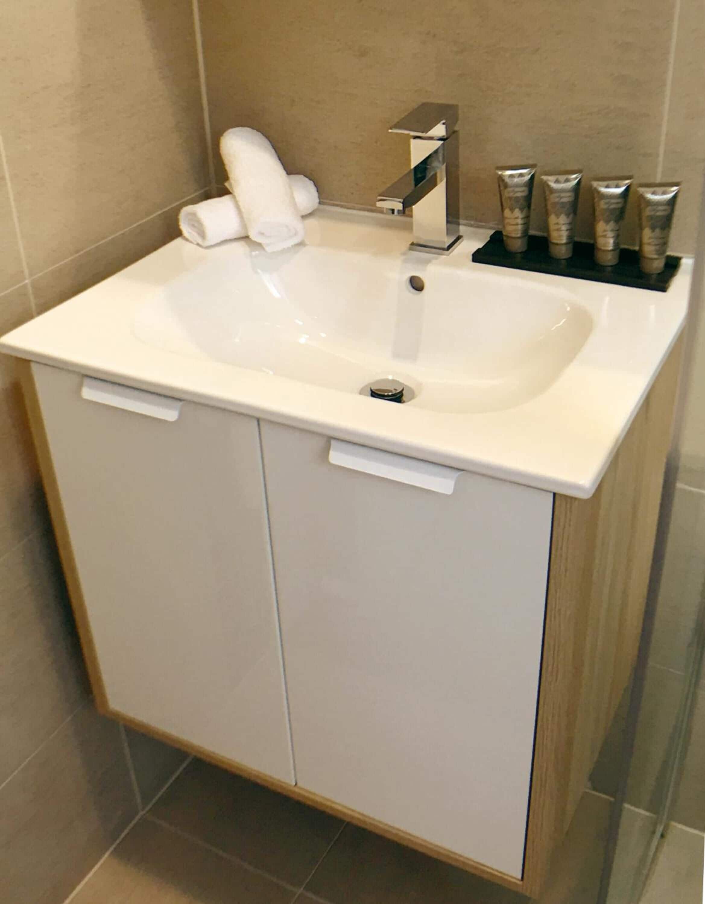 Un baño con un lavamanos blanco, un dispensador de toallas y un dispensador de jabón.