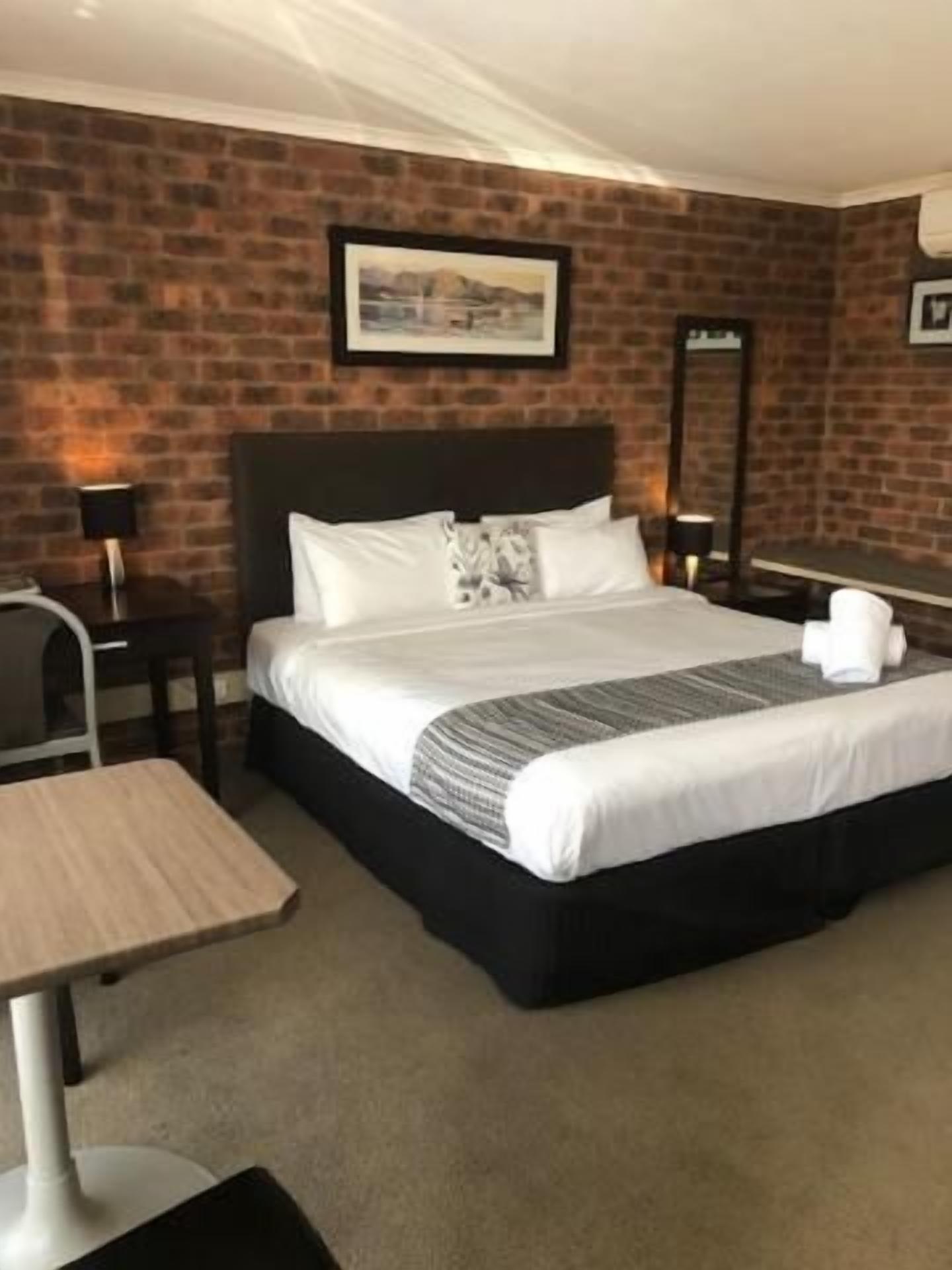 A hotel room with a large bed, a desk, and a chair.
