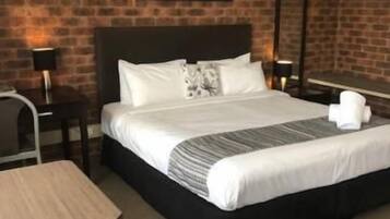 A hotel room with a large bed, a desk, and a chair.