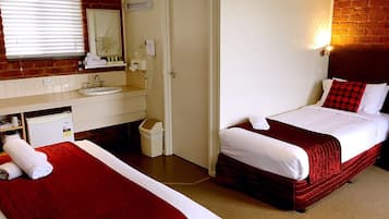 Una habitación de hotel con dos camas, un baño con lavamanos y un espejo.