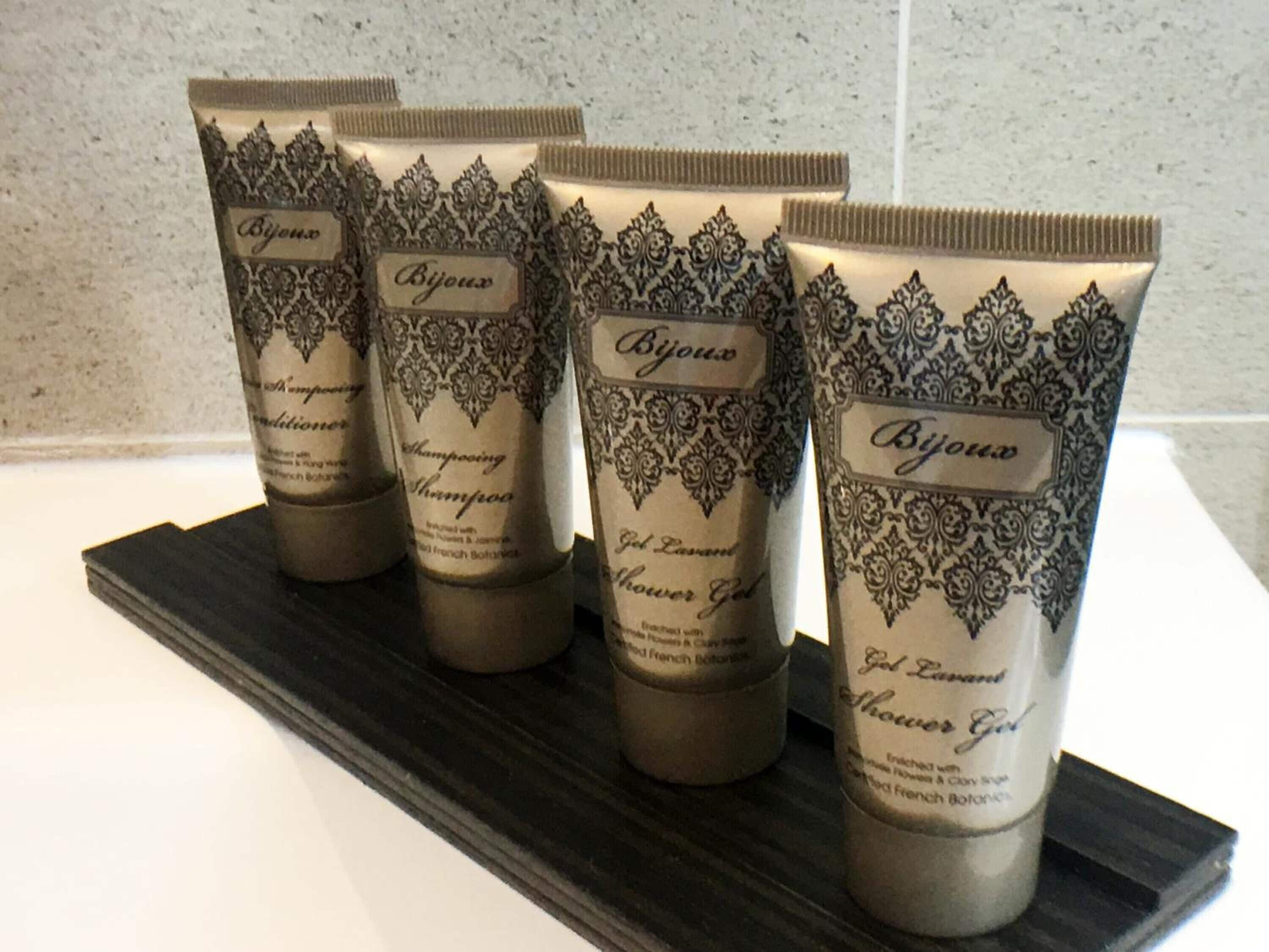 Four bottles of Bijoux shampoo and shower gel on a black tray.