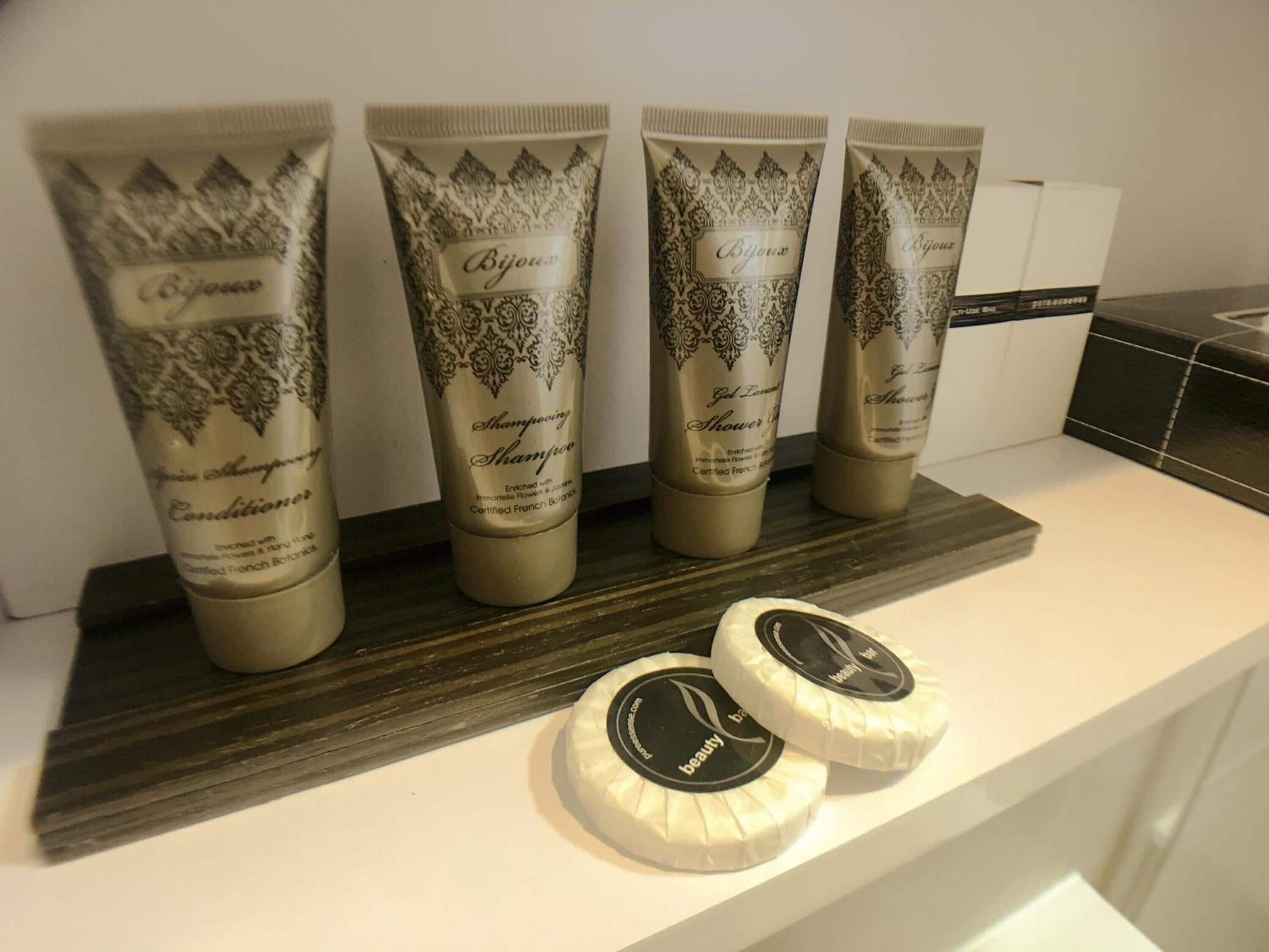 Een rij toilettasartikelen op een plank, waaronder conditioner en douchegel.