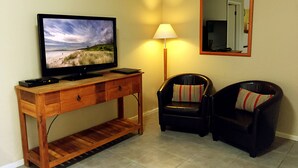 A room with a wooden desk, a television, a lamp, two leather chairs, and a mirror on the wall. - Admiral Motor Inn (Rosebud)