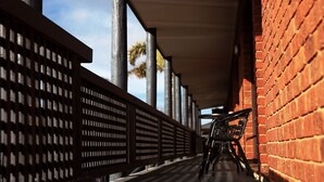 A covered walkway with a brick wall on one side and a metal railing on the other. - Admiral Motor Inn (Rosebud)
