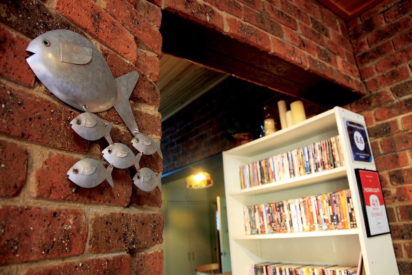 A brick wall with fish decorations and a bookshelf filled with books.