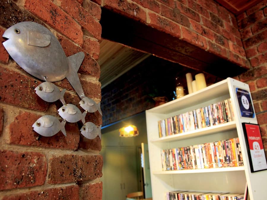 A brick wall with fish decorations and a bookshelf filled with books.