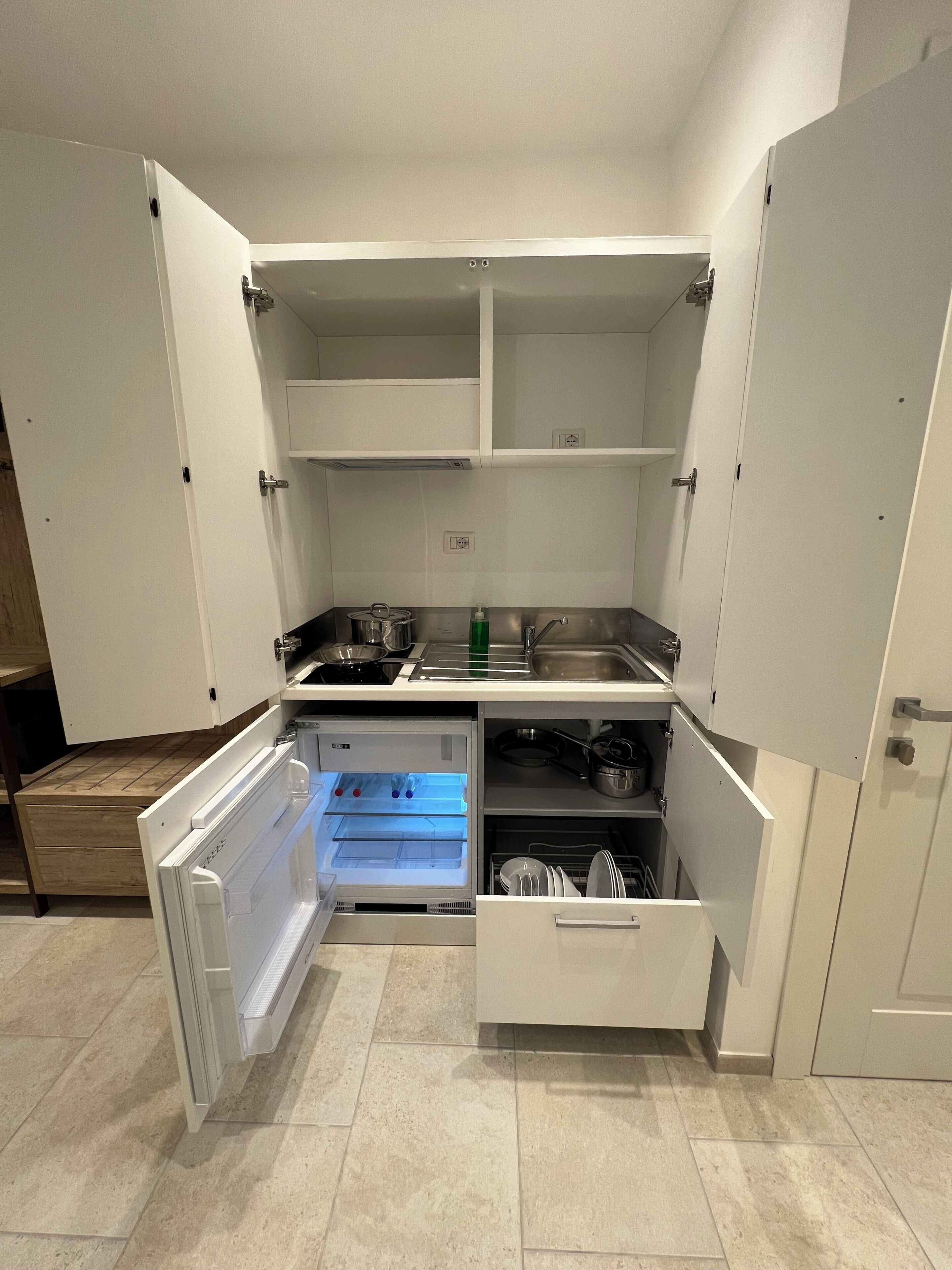A compact kitchen with a built-in refrigerator, a sink, and a microwave.