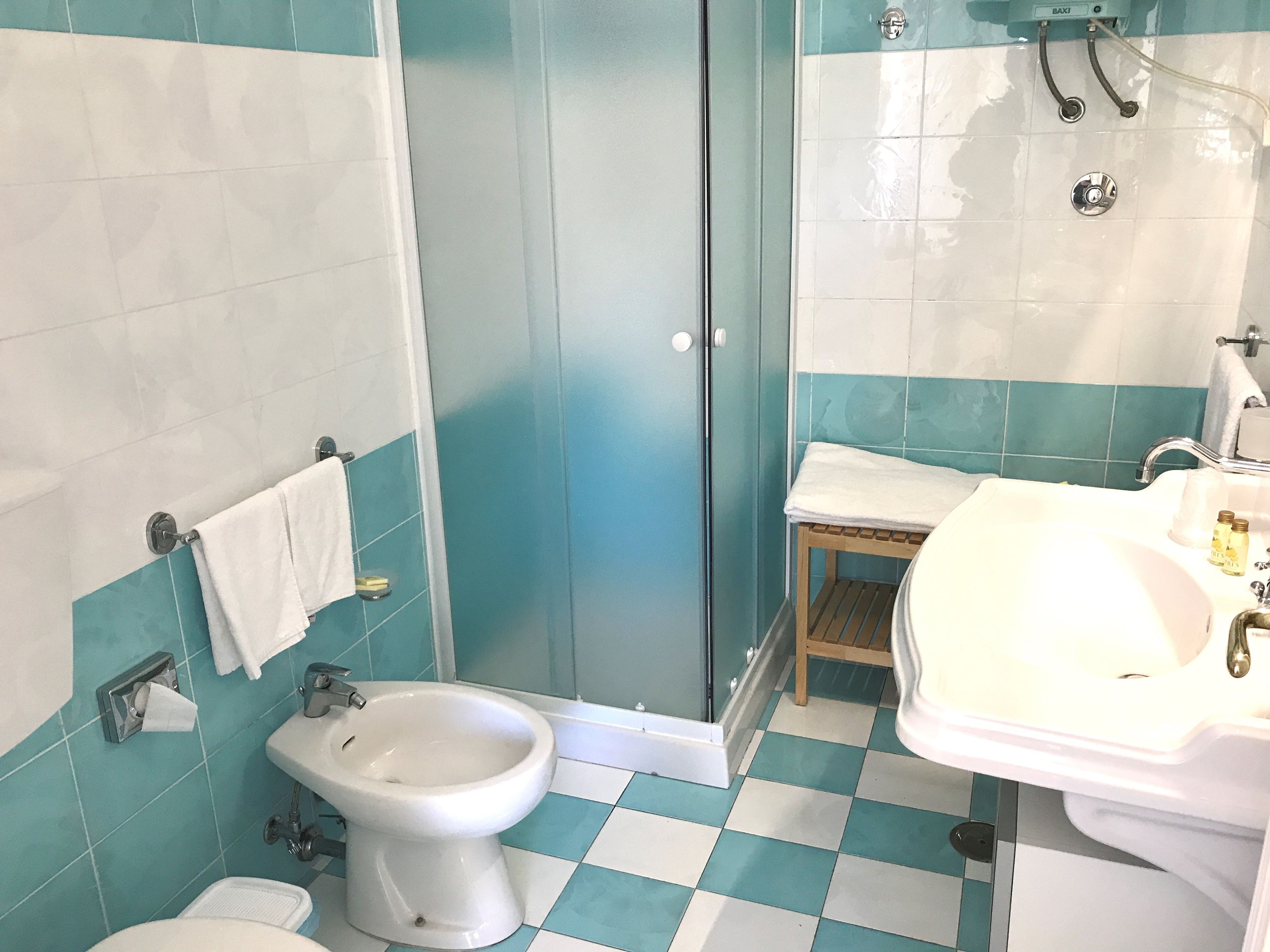 A bathroom with a bidet, a sink, and a shower stall.