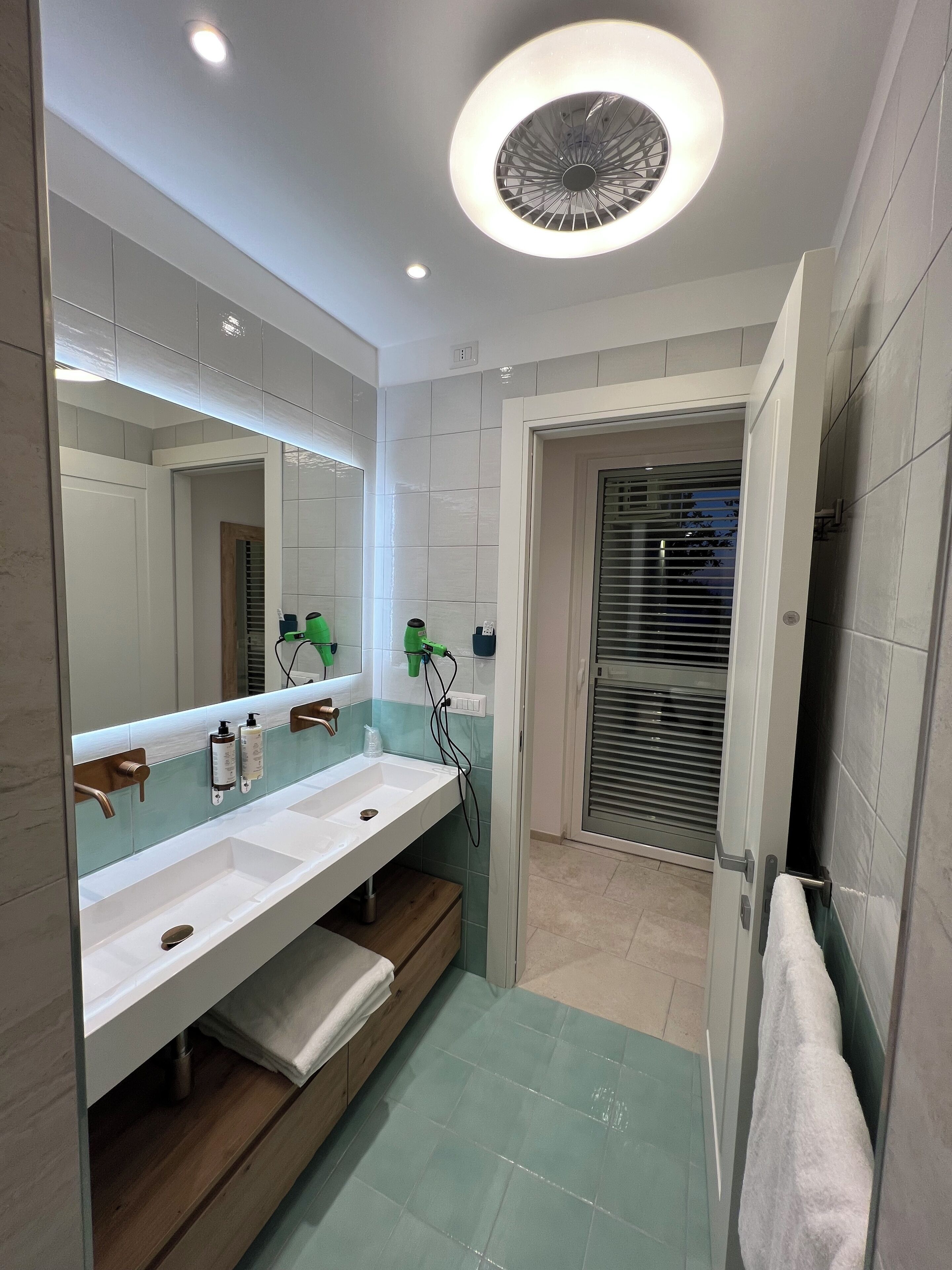 Une salle de bain moderne avec un meuble-lavabo à deux vasques, un grand miroir et un luminaire encastré au plafond.