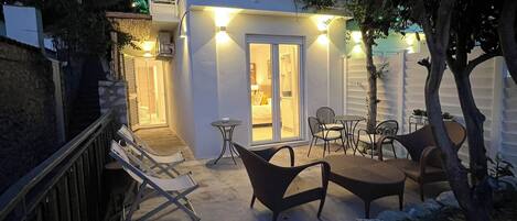 A modern house with a balcony, outdoor seating area, and a pathway leading to the entrance.