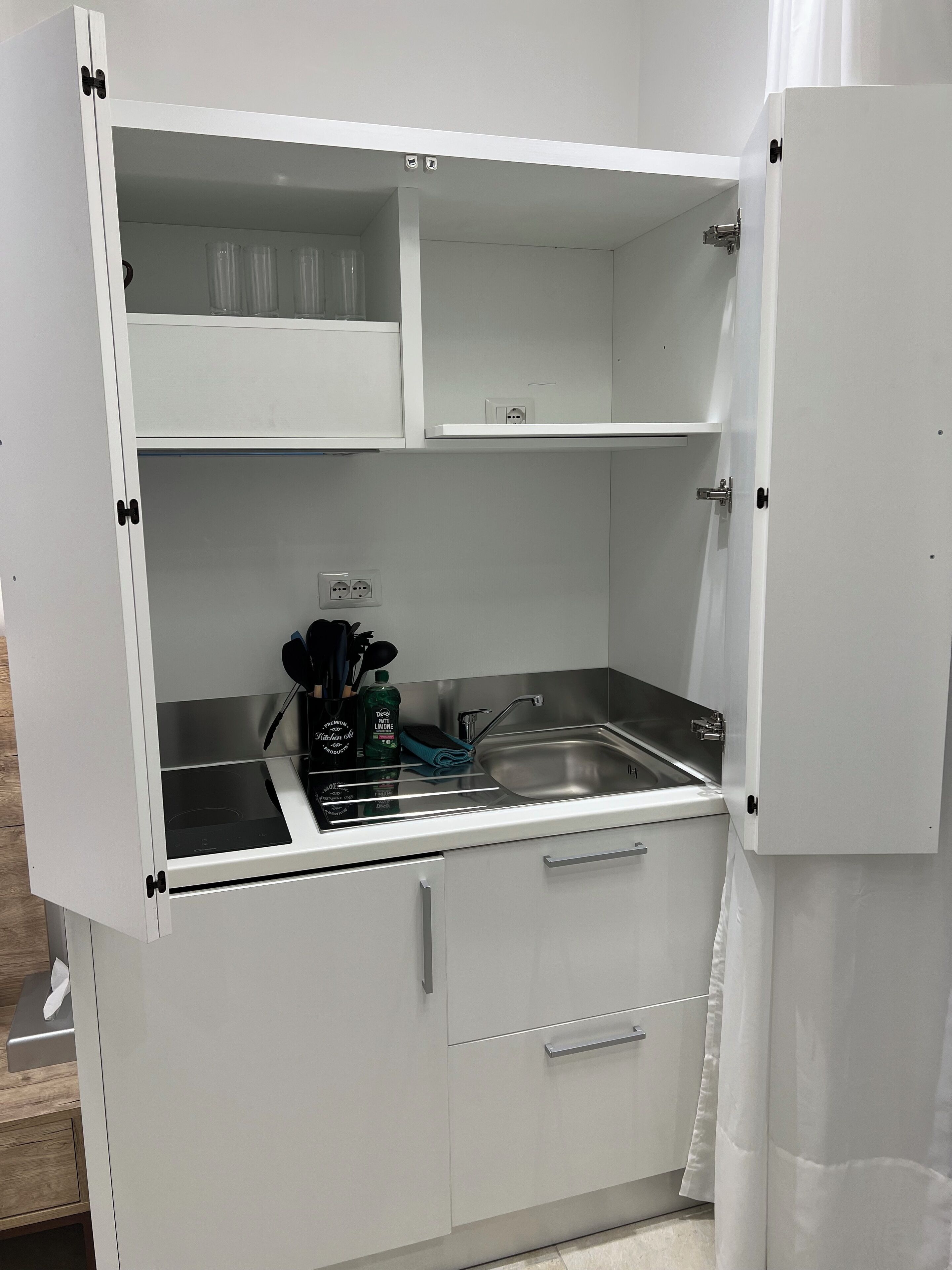 Una cocina compacta con estufa integrada, lavamanos y encimera.