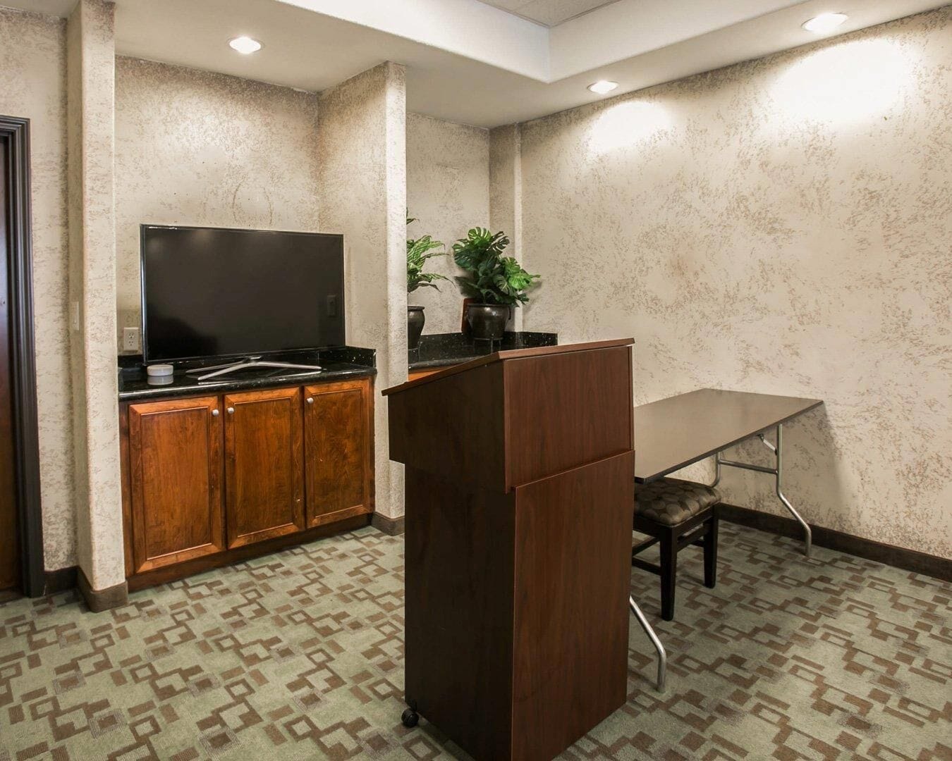 Una sala de conferencias con un armario de madera, un televisor de pantalla plana, una mesa y una silla.