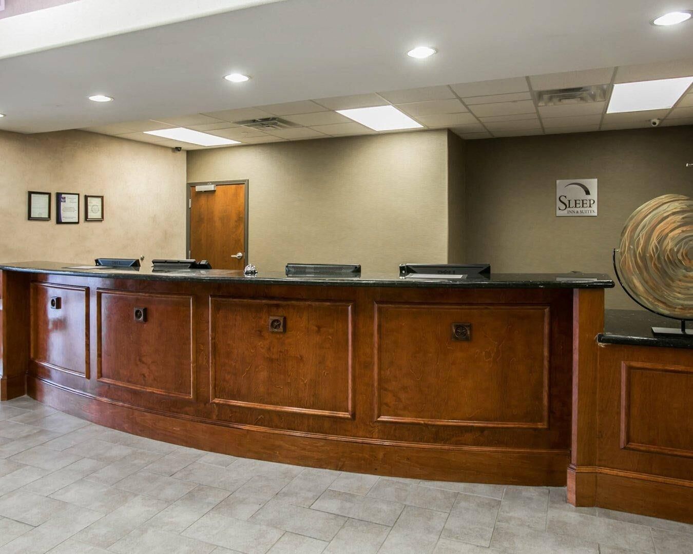 A reception desk with a wooden finish, a flat-screen TV, and a sign for Sleep Inn & Suites.