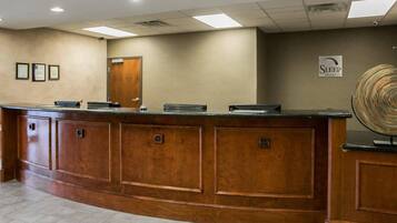 A reception desk with a wooden finish, a flat-screen TV, and a sign for Sleep Inn & Suites.