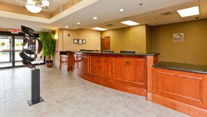 A reception area with a wooden reception desk, a chandelier, a plant, and a sign for Sleep Inn Suites. - Sleep Inn & Suites Highway 290/NW Freeway (Houston)