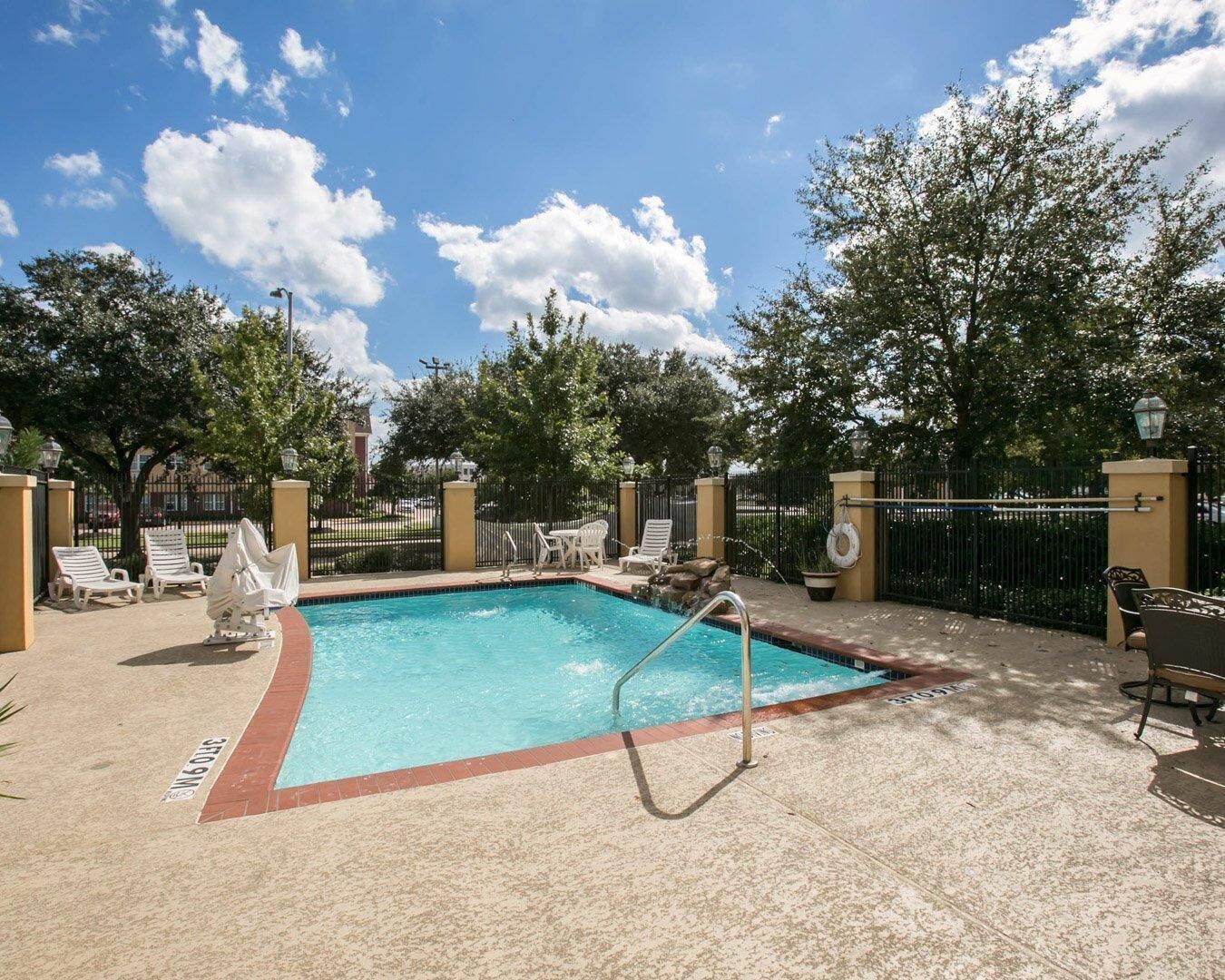 A swimming pool with lounge chairs and a paved deck.