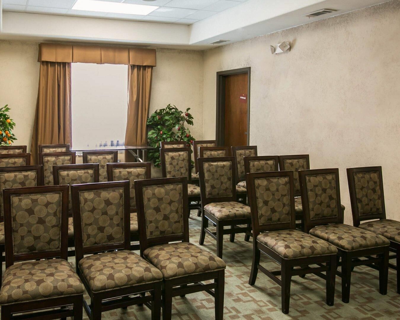 A conference room with rows of chairs, a large window with curtains, and a door labeled 'STORAGE'.
