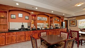 A restaurant with wooden cabinetry, a central dining table, and patterned chairs. - Sleep Inn & Suites Highway 290/NW Freeway (Houston)
