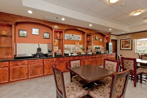 A restaurant with wooden cabinetry, a central dining table, and patterned chairs. - Sleep Inn & Suites Highway 290/NW Freeway (Houston)