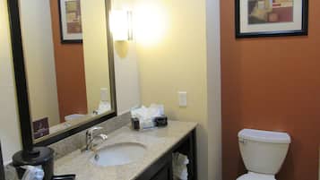 Un baño de hotel con lavabo, espejo, inodoro y toallero.
