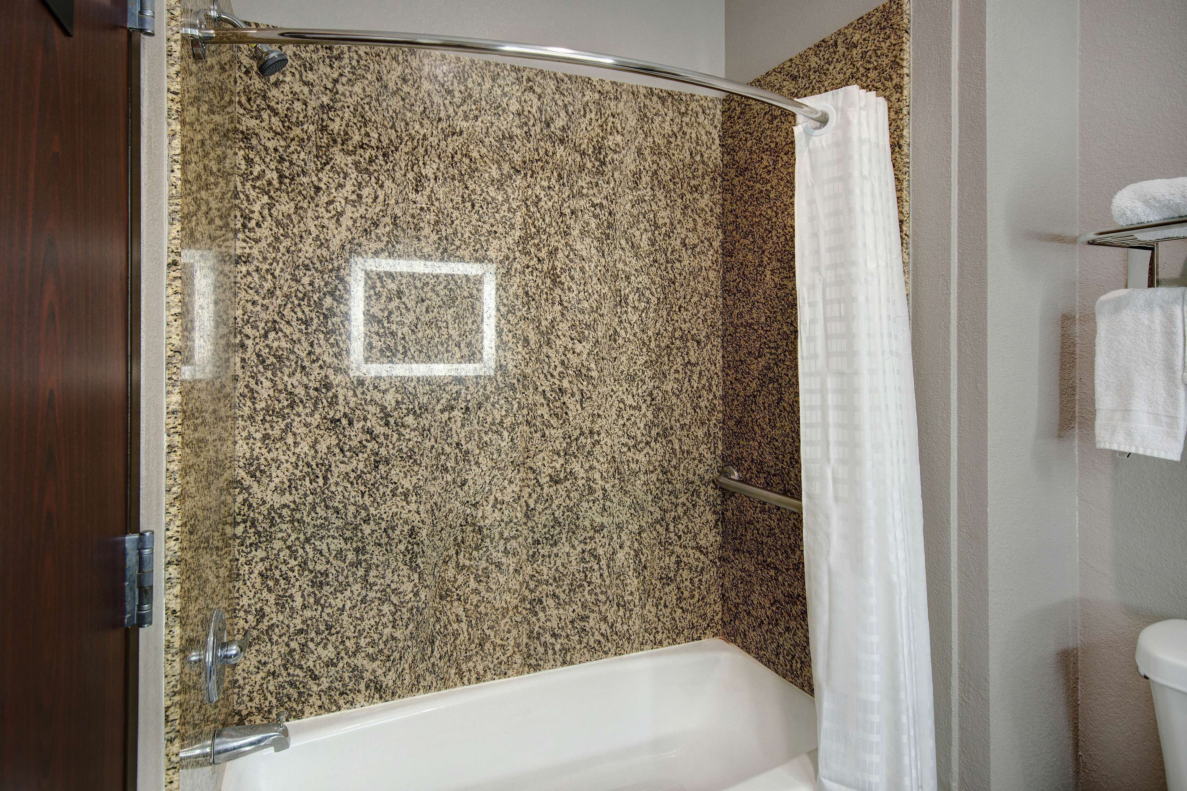 A bathroom with a bathtub, a shower curtain, and a towel rack.