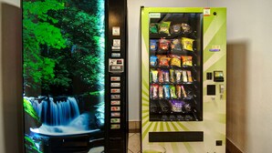 A vending machine with snacks and a water dispenser, and a digital screen displaying a waterfall. - Motel 6 Fort Worth, TX – I-35 & I-20   (Fort Worth)