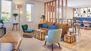 A modern living room with a sofa, chairs, a coffee table, and a wooden partition. - Kyriad Les Ulis (Les Ulis)