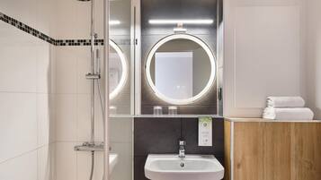 A modern bathroom with a shower, a sink, and a vanity with a mirror.
