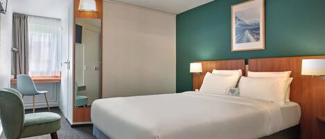 A hotel room with a large bed, a desk, a chair, and a painting on the wall.